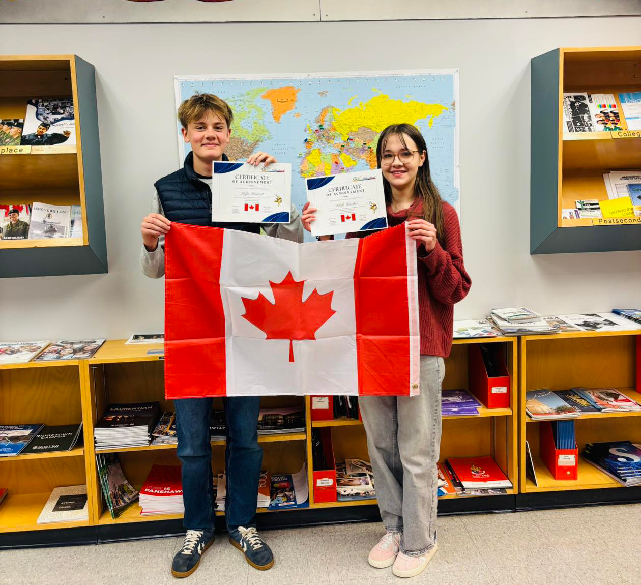 two-international-students- holding-certificate-and-canadian-flag-at-hammarskjold-high-school