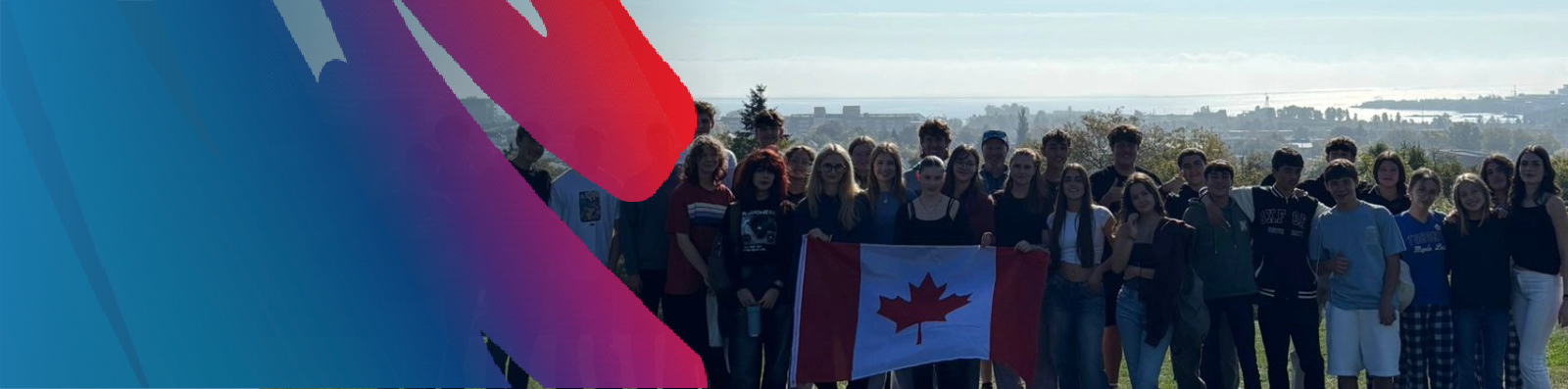 group-of-international-students-at-hillcrest-holding-canada-flag-with-city-and-lake-superior-in-background-with-lakehead-public-schools-blue-and-rainbow-logo