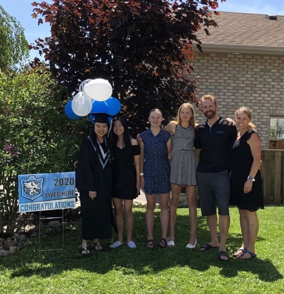 host-family-group-photo-with-family-of-four-and-two-international-students-one-in-a-graduation-gown