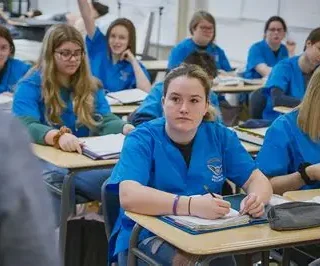 group-of-students-in-class-at-desks-wearing-blue-scrubs