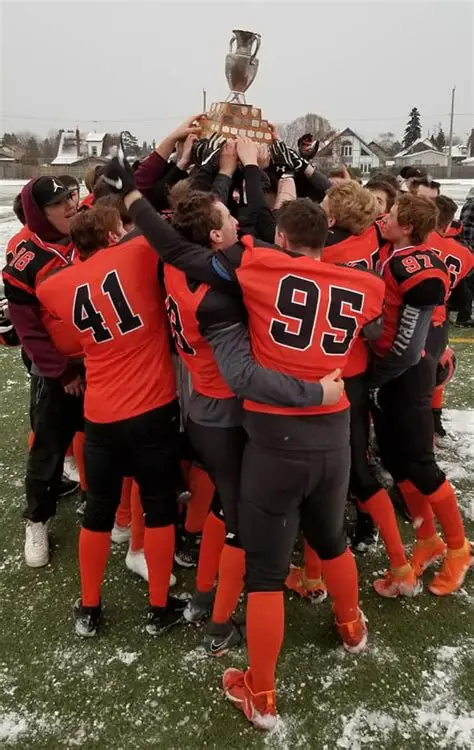 westgate-football-team-in-a-huddle-holding-trophy